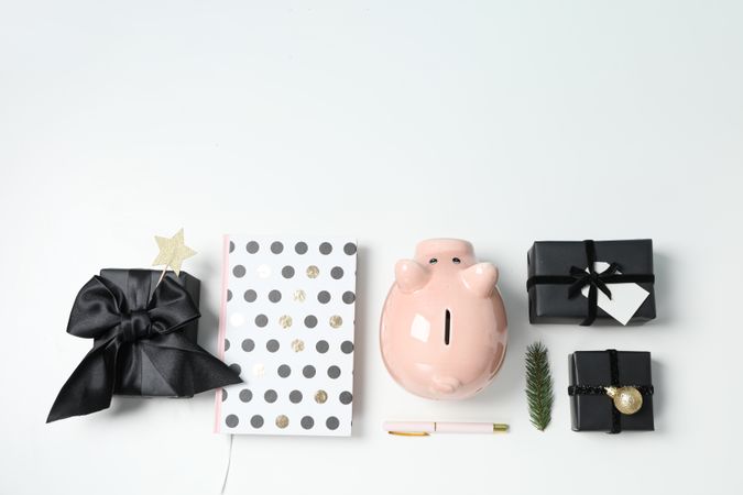 Piggy bank, gift boxes and notepads on light background, space for text