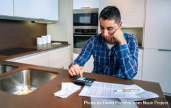Man with calculator and bills in kitchen 0Plv20
