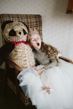 Girl sitting in chair with teddy bear