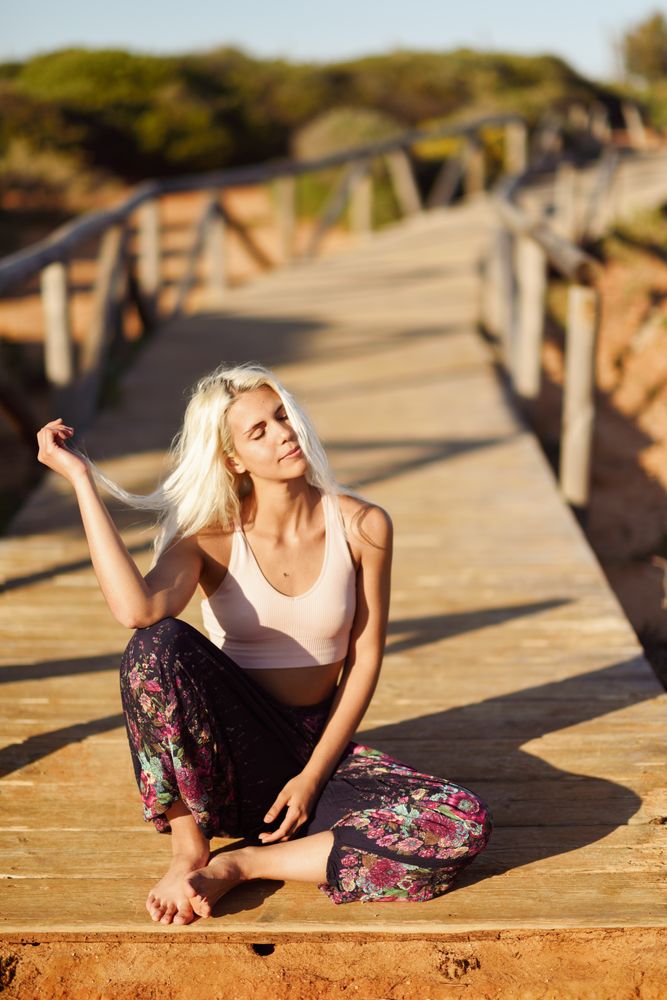Blonde woman sitting on wooden bridge