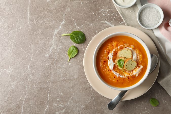 Top view of bowl of pumpkin soup on marble counter with copy space