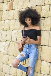 Female texting while leaning on outside wall