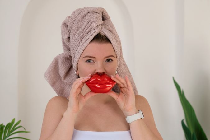 Woman using lip-shaped facial massager.
