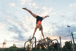 woman gymnast doing handstand on parallel bars
