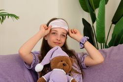 Smiling teenage girl with sleep mask and teddy bear