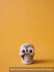 Halloween skeleton head with  googly eyes and orange background 5nkM64