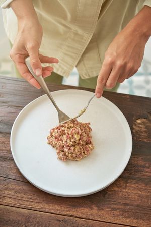 Anonymous woman putting portion of steak tartare on serving plat