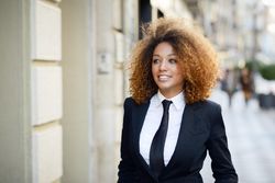 Happy female in suit walking down street outside