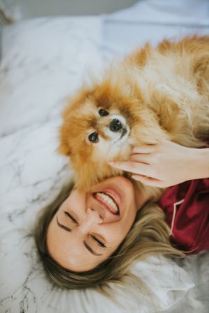 Smiling woman lying in bed with dog