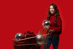 Girl in red sweater holds disco ball near shopping cart