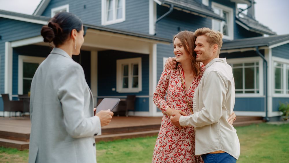 Successful Couple Striking Deal with Realtor in Front of Their New Home.
