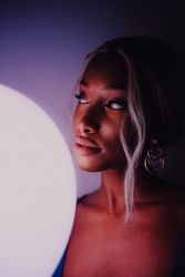 Black adult woman with illuminated balloon in darkness looking at camera