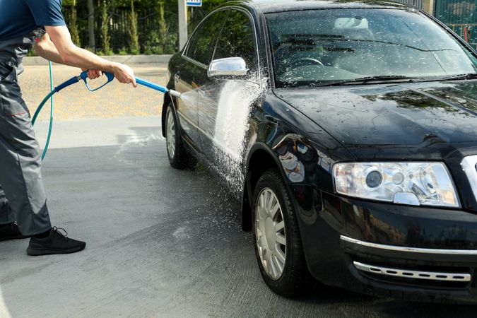 A man washes a car in a manual car wash. Clear car