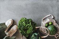 Overhead shot of grocery shopping jute full of fresh produce, with shoes, mesh bag, copy space