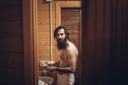 Bearded man brushing teeth in wooden house