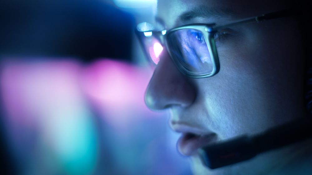 Close-up of Man Wearing Glasses Playing Video Games in His Headset Giving Commands into Microphone.