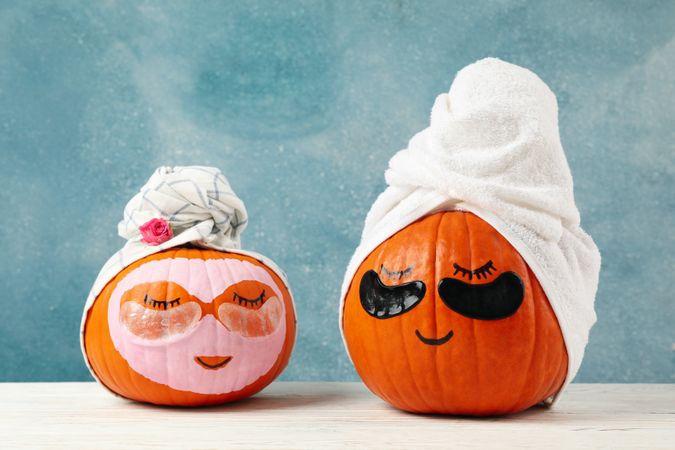 Pumpkins with eye patches and towels on blue background