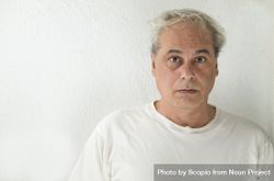 Portrait of surprised middle aged man in light shirt against light wall bEXmM4