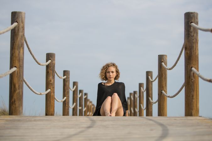 Young woman sitting on footbridge