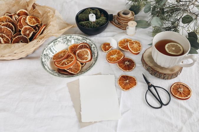 Traditional Christmas still life with cup of tea, dry oranges and pine, eucalyptus tree branches on linen table cloth