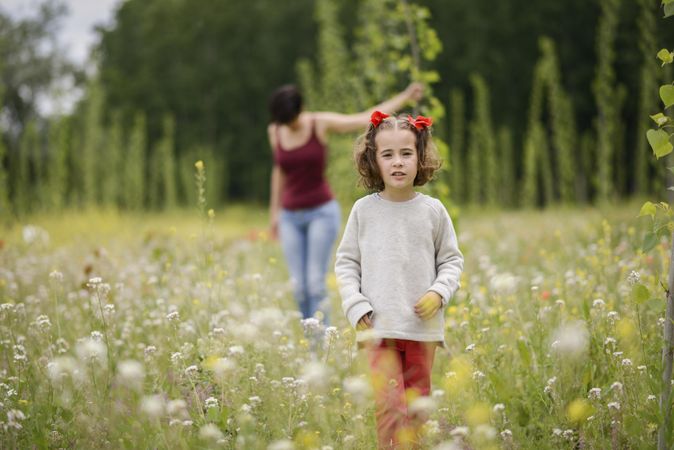 Girl walking in field with woman behind her