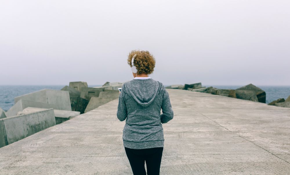 Back view of woman with headphones using smartphone