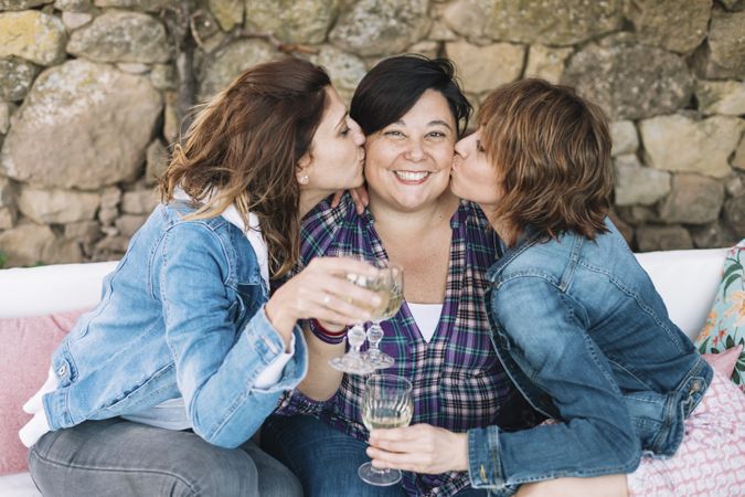 Portrait of three woman having fun kissing friend outdoors and smiling