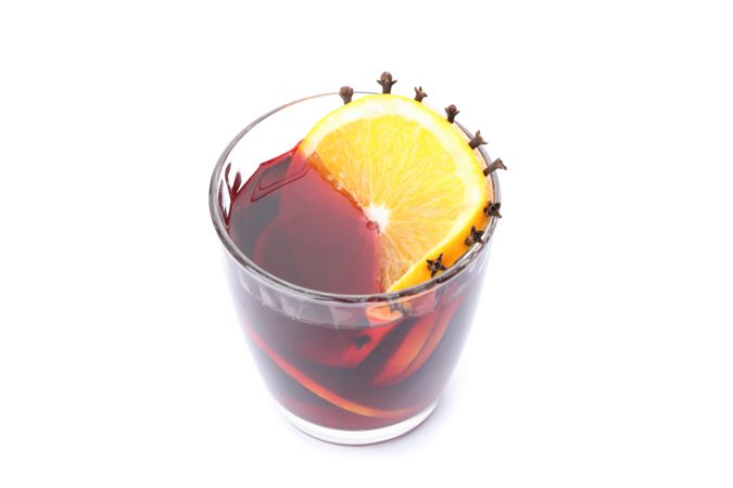 Glass of tasty mulled wine with orange isolated on studio background