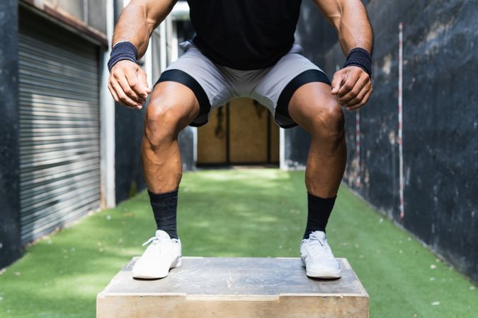 Anonymous athlete jumping on wooden box