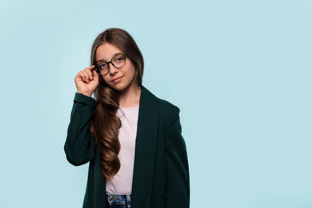 Teen girl adjusting glasses, wearing blazer