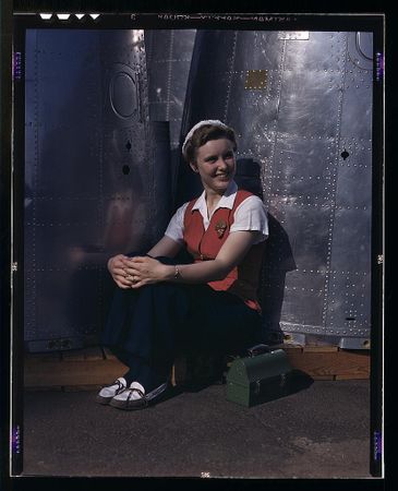 Long Beach, CA, USA - 1942: Woman sitting with lunch box among airplane parts