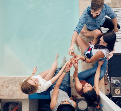 Top view of group of friends toasting at party by a swimming pool