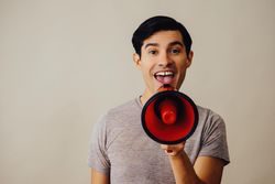 Hispanic male speaking through red loudspeaker