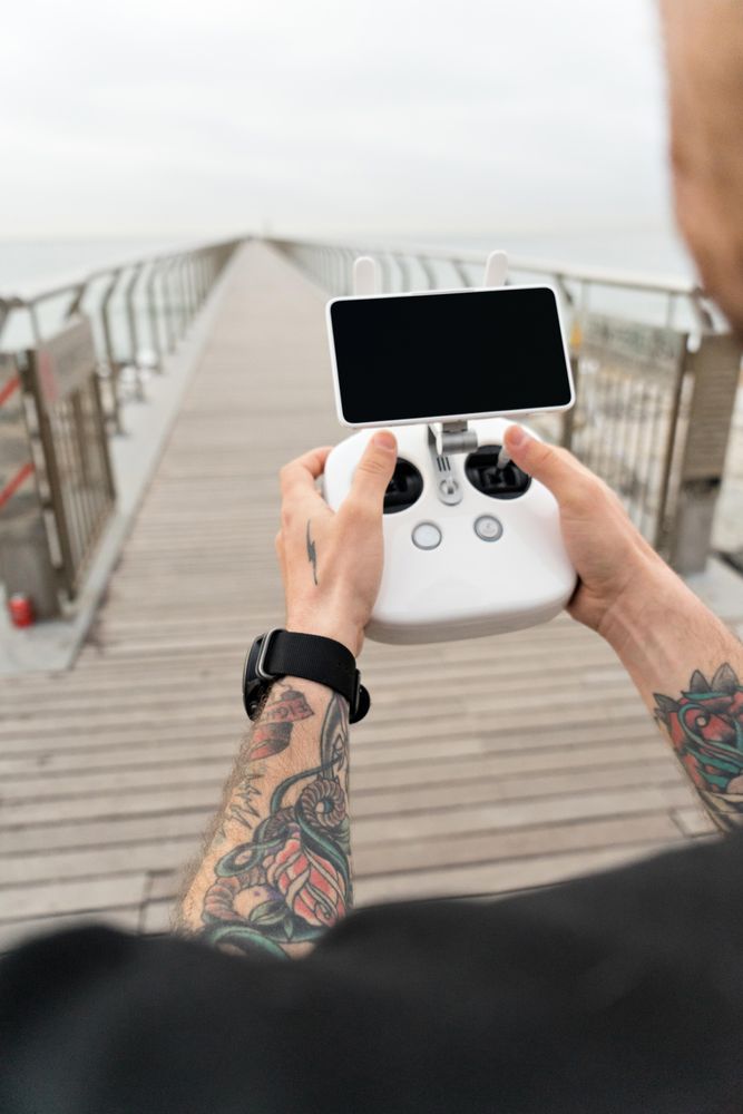 Man with remote for drone on boardwalk on beach