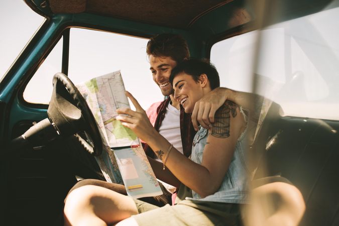 Young couple smiling while planning road trip destination