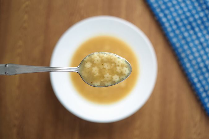 Top view of spoon with star pasta soup