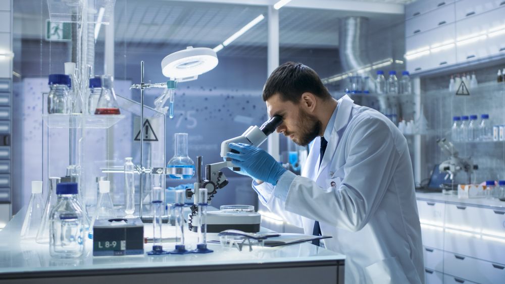 Research Scientist Looks into Microscope.