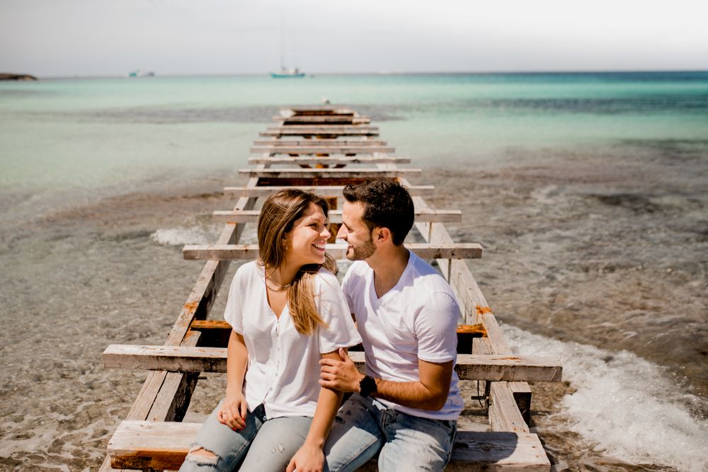 Glad lovers sitting on destroyed pier on seashore