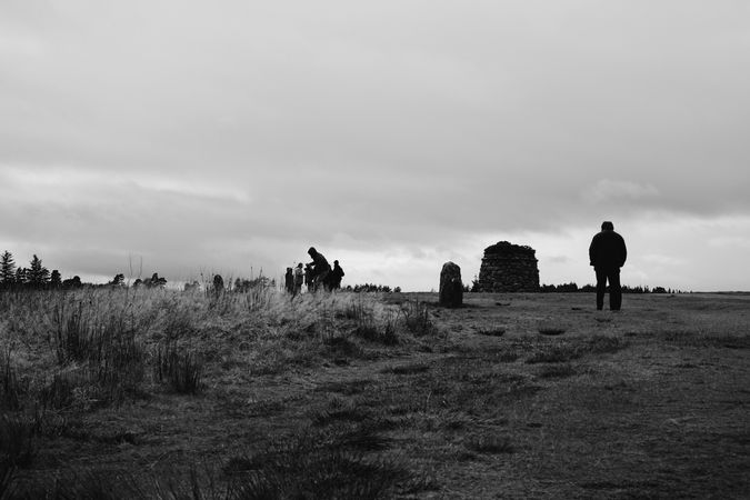 Grayscale photo of people standing on grass field