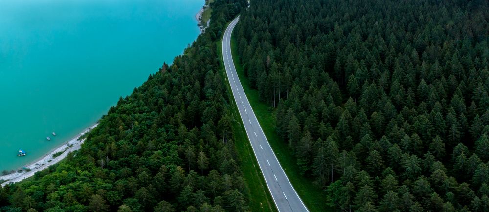 Drone aerial view with Sylvenstein lakeshore and road through the forest