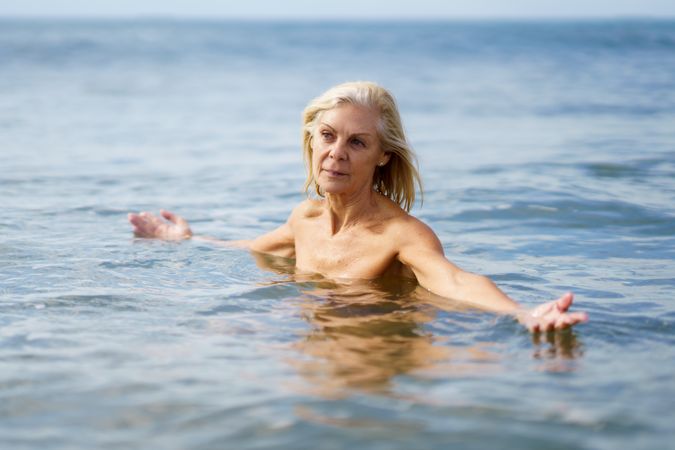Older woman in bathing in the sea with open arms