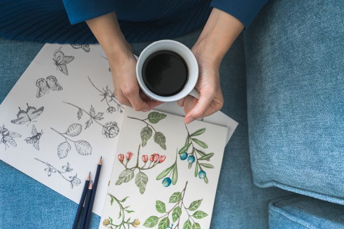 Young anonymous woman with coffee looking album with pictures