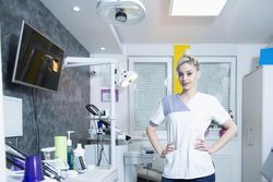 Attractive dentist in her office with hands on her hips