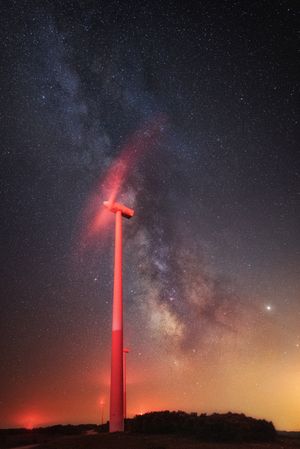 Illuminated wind turbine over starry night sky