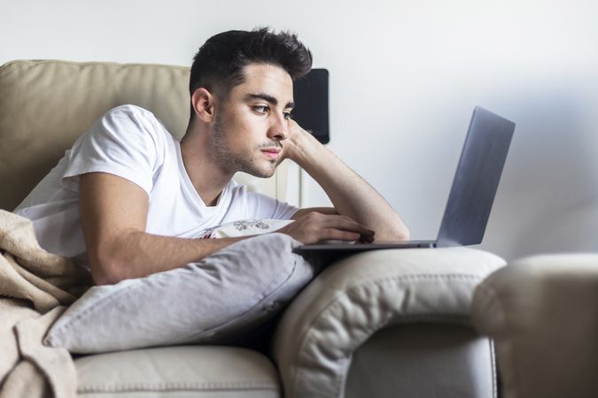 Young man relaxing on sofa while using laptop