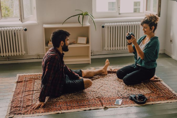 Woman photographing boyfriend on camera while resting at home