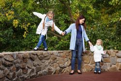Mother with two girls walking along wall in park
