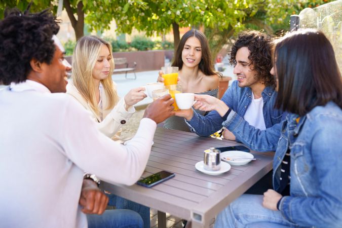 Men and women celebrating with juice and coffee at an outdoor restaurant