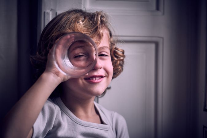 Positive little kid smiling and looking at camera through glass
