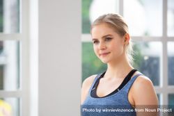 Blonde woman standing in bright room wearing work out clothes bEDN14
